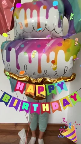 Woman celebrating among balloons, confetti, and a Happy Birthday banner